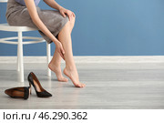 Tired young woman feeling ache in legs indoors. Стоковое фото, фотограф Pixel_shot / Фотобанк Лори