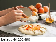 Woman smearing raw peach galette with egg yolk, closeup. Стоковое фото, фотограф Pixel_shot / Фотобанк Лори