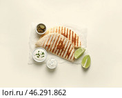 Parchment with tasty quesadillas, lime, sauces and pickled jalapenos on white background. Стоковое фото, фотограф Pixel_shot / Фотобанк Лори