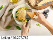 Woman grating cheese onto plate with tasty pasta, top view. Стоковое фото, фотограф Pixel_shot / Фотобанк Лори