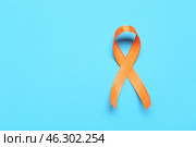 Orange ribbon on blue background. Multiple Sclerosis Awareness Month. Стоковое фото, фотограф Pixel_shot / Фотобанк Лори