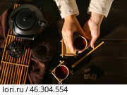 Female hands with cup of hot puer tea and dry pressed leaves on dark wooden table. Стоковое фото, фотограф Pixel_shot / Фотобанк Лори