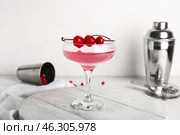 Glass of Cosmopolitan cocktail with cherries on white background. Стоковое фото, фотограф Pixel_shot / Фотобанк Лори
