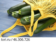 Mesh shopping bag with fresh zucchini squashes on wooden background. Стоковое фото, фотограф Pixel_shot / Фотобанк Лори