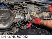 Car repair. A mechanic installs an air supply pipe onto the engine throttle valve. Стоковое фото, фотограф Коханова Наталья / Фотобанк Лори