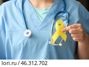 Doctor holding yellow ribbon, closeup. Sarcoma concept. Стоковое фото, фотограф Pixel_shot / Фотобанк Лори