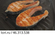 There are two pieces of broiled salmon steaks in square black frying pan. Стоковое видео, видеограф Яков Филимонов / Фотобанк Лори