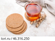 Drink coasters with cup of tea and wafer rolls on white table. Стоковое фото, фотограф Pixel_shot / Фотобанк Лори