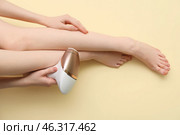 Beautiful young woman epilating legs on beige background. Стоковое фото, фотограф Pixel_shot / Фотобанк Лори