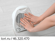 Woman warming near electric fan heater at home, closeup. Стоковое фото, фотограф Pixel_shot / Фотобанк Лори