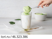 Woman preparing tasty dalgona matcha latte on light wooden background. Стоковое фото, фотограф Pixel_shot / Фотобанк Лори