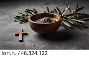 Religion, faith, liturgy, Ash Wednesday. Great lent. A wooden cross, a ceremonial bowl made of ash and an olive branch on a gray background. Стоковое AI-изображение, AI-художник Photojuli / Фотобанк Лори