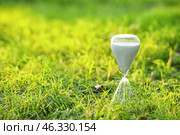 Stylish hourglass on grass outdoors. Стоковое фото, фотограф Pixel_shot / Фотобанк Лори