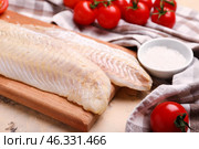 Wooden board with raw codfish fillet on beige background. Стоковое фото, фотограф Pixel_shot / Фотобанк Лори
