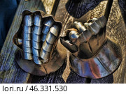 Medieval gauntlets, also known as gauntlets. These metal gloves are part of a knight's armor and served to protect the hands in combat. They consist of movable segments connected by rivets, which allows the fingers to be flexible when holding a weapon. Traces of use are visible, which gives them an authentic look.Such gauntlets were used in Europe in the 14th-15th centuries and were an important part of the armor, protecting the hands from blows from swords, axes and other types of bladed weapons. Стоковое фото, фотограф Анна Кривицкая / Фотобанк Лори