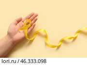 Female hand and yellow ribbon on color background. Sarcoma concept. Стоковое фото, фотограф Pixel_shot / Фотобанк Лори