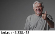 Senior man showing thumbs up on gray background. Стоковое видео, видеограф Данил Руденко / Фотобанк Лори