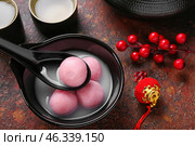 Spoon and bowl of tangyuan with Chinese decor on grunge background, closeup. Dongzhi Festival. Стоковое фото, фотограф Pixel_shot / Фотобанк Лори
