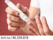 Diabetic man taking blood sample with lancet pen on color background, closeup. Стоковое фото, фотограф Pixel_shot / Фотобанк Лори