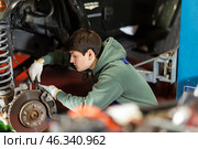 Auto mechanic connects brake hose to front wheel hub of car. Стоковое фото, фотограф Яков Филимонов / Фотобанк Лори