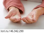 Hands of elderly woman with rice on white background. Concept of poverty. Стоковое фото, фотограф Pixel_shot / Фотобанк Лори