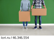 Young couple with boxes near color wall indoors. Moving into new house. Стоковое фото, фотограф Pixel_shot / Фотобанк Лори