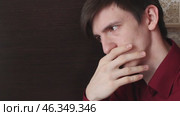 Young guy in a red shirt touches his lips with the fingers of his right hand, doubts looks. Стоковое видео, видеограф Vladislav_v / Фотобанк Лори