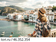 A girl traveler with a backpack on the background of the southern coast of the sea. A woman travels, enjoys life and the environment. Tourism. Стоковое AI-изображение, AI-художник Photojuli / Фотобанк Лори