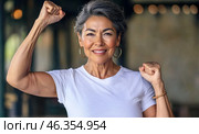 Middle aged hispanic woman with raised fist of empowerment, strength and women solidarity, International Womens Day concept. Стоковое AI-изображение, AI-художник Анастасия Золотницкая / Фотобанк Лори