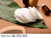 Cotton pads, comb, cosmetic products and tropical leaf on color background, closeup. Стоковое фото, фотограф Pixel_shot / Фотобанк Лори
