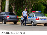 Russia, Samara. June 22, 2014. A traffic police inspector removed a license plate from a car for violating traffic rules on a sunny summer day. Text in Russian:police slow down. Редакционное фото, фотограф Акиньшин Владимир / Фотобанк Лори