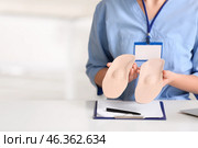 Young female nurse holding orthopedic insoles in clinic, closeup. Стоковое фото, фотограф Pixel_shot / Фотобанк Лори