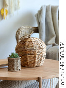 Wicker basket on coffee table near rattan armchair in living room, closeup. Стоковое фото, фотограф Pixel_shot / Фотобанк Лори