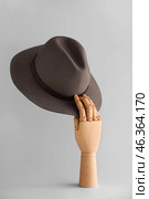 Wooden mannequin holding fedora hat on grey background. Стоковое фото, фотограф Pixel_shot / Фотобанк Лори
