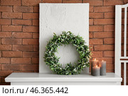 Christmas mistletoe wreath, painting and candles on mantelpiece near brick wall. Стоковое фото, фотограф Pixel_shot / Фотобанк Лори