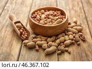 Bowl and scoop with tasty peanuts on wooden table. Стоковое фото, фотограф Pixel_shot / Фотобанк Лори