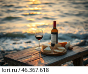 A table with wine and cheese on the very shore of the sea. The setting sun illuminates the table and the beach. Стоковое AI-изображение, AI-художник Iva Noel / Фотобанк Лори