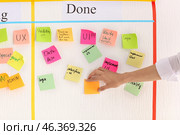 Man attaching sticky note to scrum task board in office. Стоковое фото, фотограф Pixel_shot / Фотобанк Лори