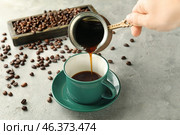 Woman pouring hot coffee from jezve into cup on table. Стоковое фото, фотограф Pixel_shot / Фотобанк Лори