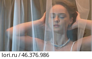 Slow motion video of young female covered with veil. Woman is dressed in a peignoir and wears a necklace and earrings. Стоковое видео, видеограф Сергей Пристяжнюк (Serg Zastavkin) / Фотобанк Лори