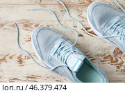 Pair of sportive shoes with untied laces on light wooden background, closeup. Стоковое фото, фотограф Pixel_shot / Фотобанк Лори