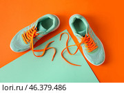 Pair of sportive shoes with untied laces on color background. Стоковое фото, фотограф Pixel_shot / Фотобанк Лори