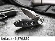 Folding pocket knife with rubberized handle on black textured background. Стоковое фото, фотограф Pixel_shot / Фотобанк Лори