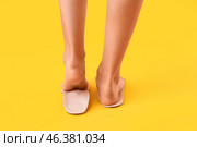 Female feet and orthopedic insoles on yellow background. Стоковое фото, фотограф Pixel_shot / Фотобанк Лори