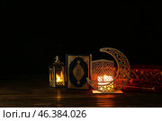 Arabic candle holder with glowing candle, fanoos lamp and Quran on dark background. Стоковое фото, фотограф Pixel_shot / Фотобанк Лори