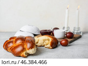 Traditional challah bread with glowing candles and Jewish caps on light background. Shabbat Shalom. Стоковое фото, фотограф Pixel_shot / Фотобанк Лори