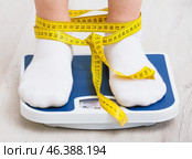 Skinny woman with measuring tape standing on floor scales. Concept of anorexia. Стоковое фото, фотограф Pixel_shot / Фотобанк Лори