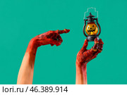 Bloodstained zombie hands with Halloween lantern on green background. Стоковое фото, фотограф Pixel_shot / Фотобанк Лори