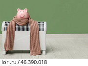 Electric convector heater, piggy bank and scarf near green wall. Heating season. Стоковое фото, фотограф Pixel_shot / Фотобанк Лори
