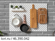 White pegboard with frying pan, strainer, cutting boards and houseplants hanging on grey brick wall in kitchen. Стоковое фото, фотограф Pixel_shot / Фотобанк Лори